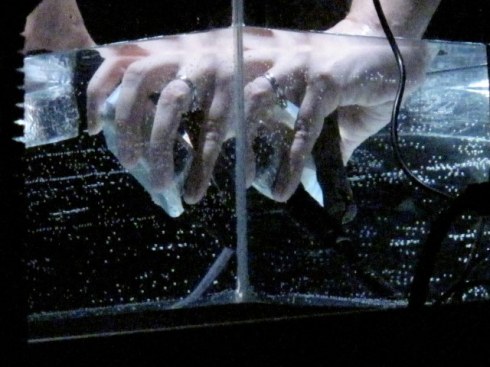 les mains de l'artiste manipulent un micro dans l'eau